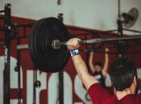 man carrying barbell at the gym