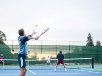 four men playing double tennis during daytime